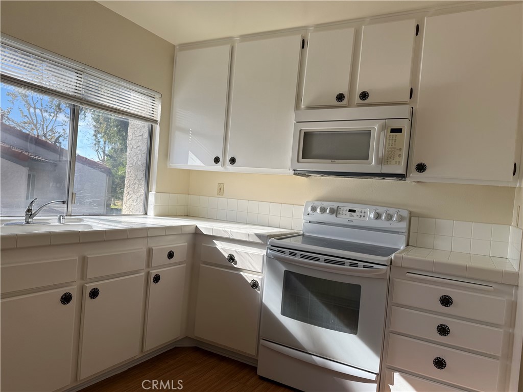 19547 Rinaldi Street, Unit 27 Porter Ranch, CA 91326 - Photo 19 of 20 a kitchen with cabinets appliances and a sink