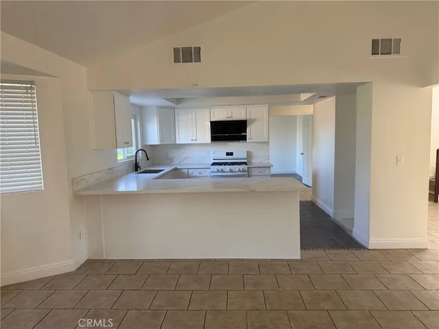 a living room with stainless steel appliances kitchen island granite countertop a sink and cabinets