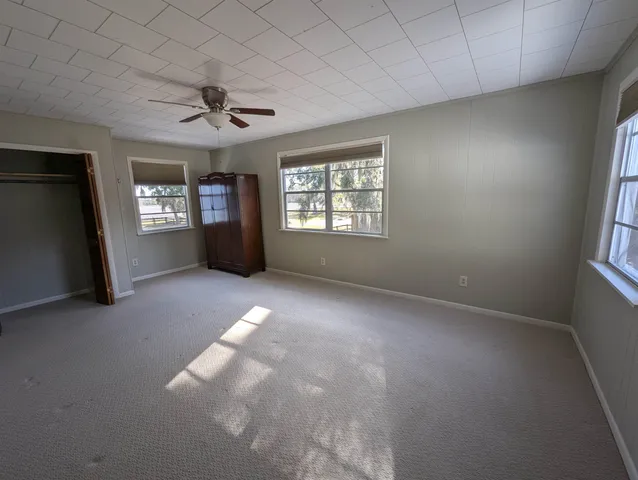 en empty room with windows and ceiling fan
