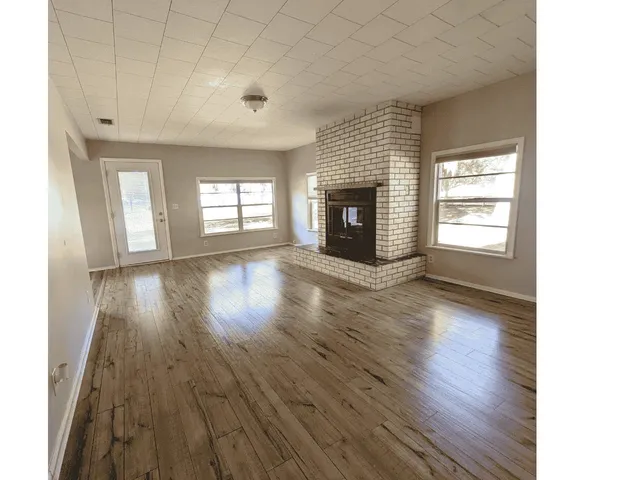 an empty room with wooden floor and fireplace