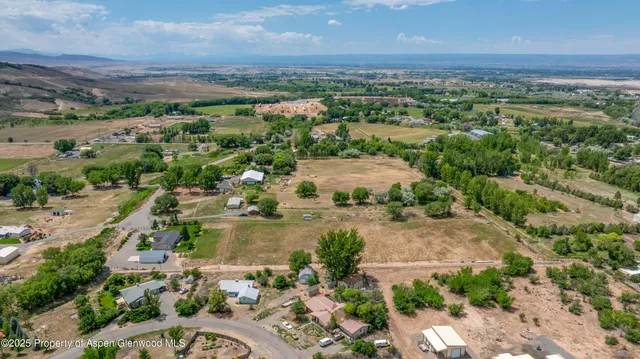 an aerial view of residential houses with outdoor space and trees