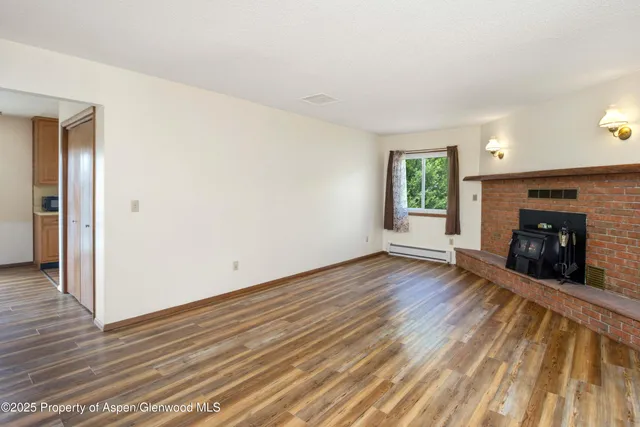 an empty room with wooden floor fireplace and windows