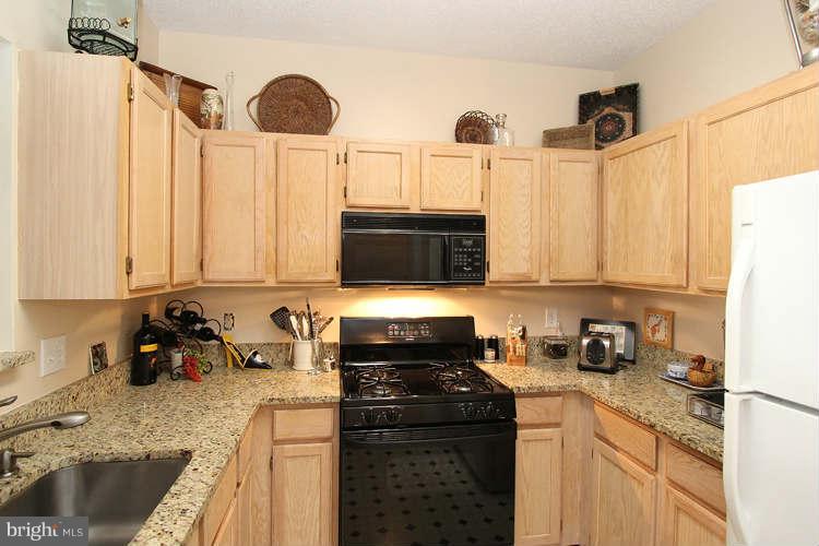 12009 Taliesin Place, Unit 14 Reston, VA 20190 - Photo 5 of 15 a kitchen with stainless steel appliances a stove a sink a refrigerator and cabinets