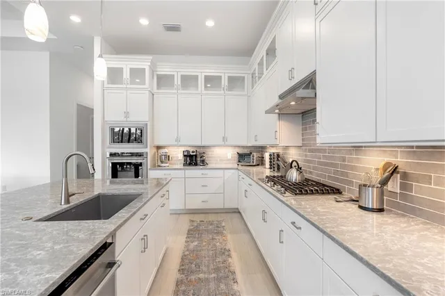 a large kitchen with stainless steel appliances granite countertop a sink stove and cabinets