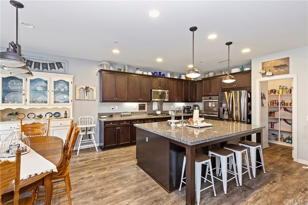 28212 Rustling Wind Circle Menifee, CA 92585 - Photo 9 of 28 a kitchen with stainless steel appliances granite countertop a stove a refrigerator a kitchen island a dining table and chairs