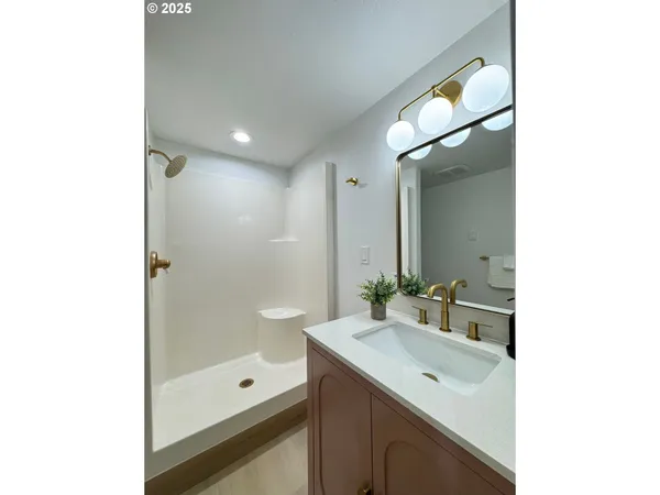 a bathroom with a bathtub shower sink vanity and mirror