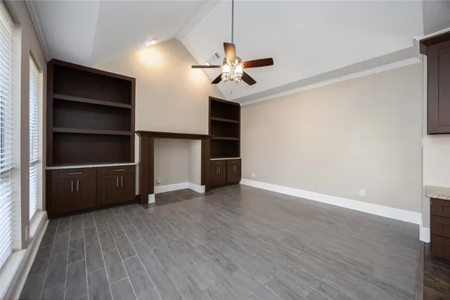 a view of an empty room with a window and wooden floor