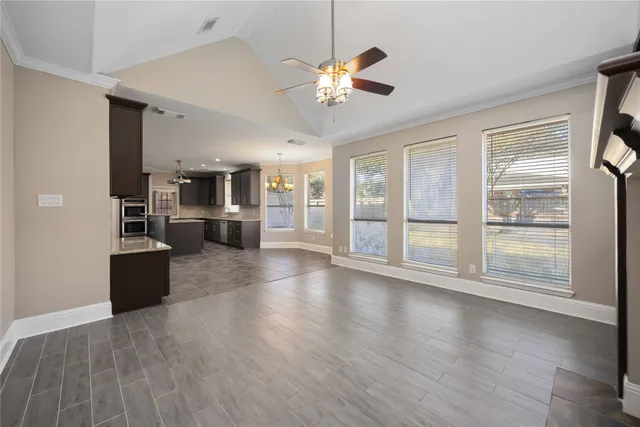 a view of a livingroom with furniture wooden floor a ceiling fan and windows