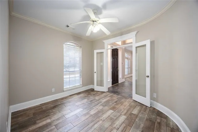 an empty room with wooden floor ceiling fan and windows