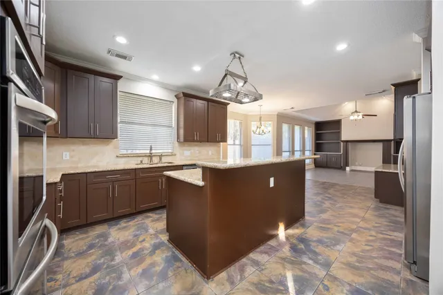 a kitchen with stainless steel appliances granite countertop a refrigerator a sink dishwasher a stove and a sink with granite countertops