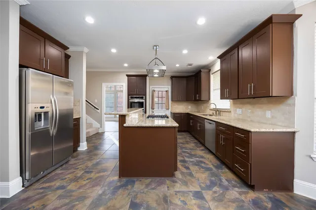 a large kitchen with stainless steel appliances granite countertop a refrigerator a sink a stove and a wooden floors