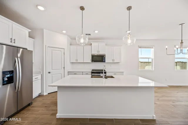 a large kitchen with stainless steel appliances kitchen island a stove a refrigerator a oven and a sink with cabinets