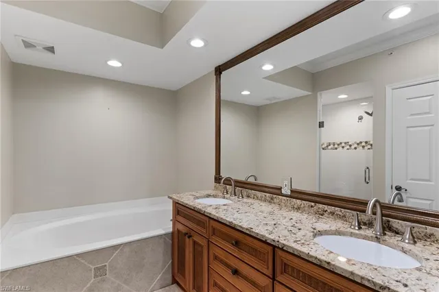 a bathroom with a granite countertop bathtub a double vanity sink and mirror