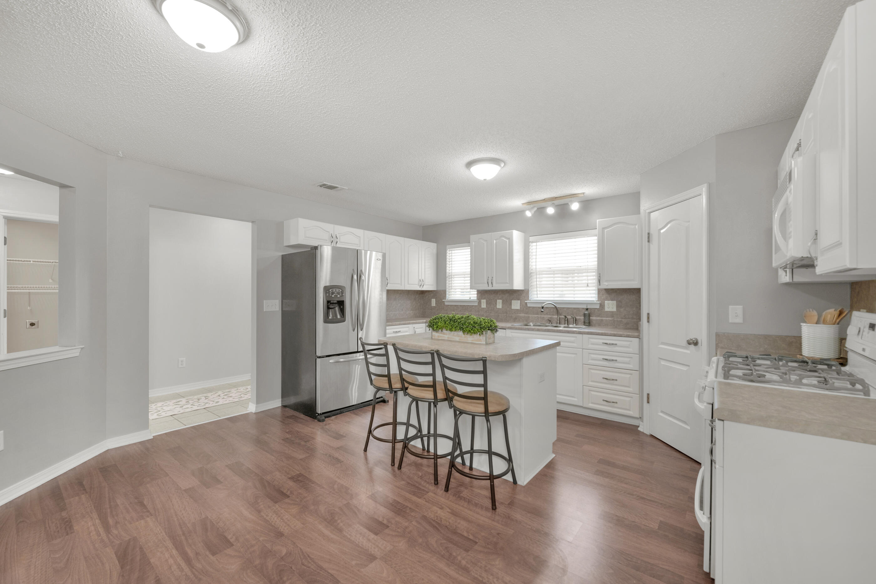 706 Riva Ridge Drive Crestview, FL 32539 - Photo 9 of 22 a kitchen with stainless steel appliances granite countertop a refrigerator a microwave oven a sink dishwasher and white cabinets with wooden floor