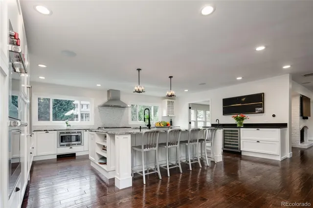 a kitchen with stainless steel appliances kitchen island granite countertop a stove top oven a sink a dining table and chairs