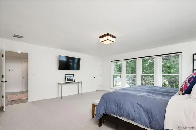 a spacious bedroom with a bed and a flat screen tv