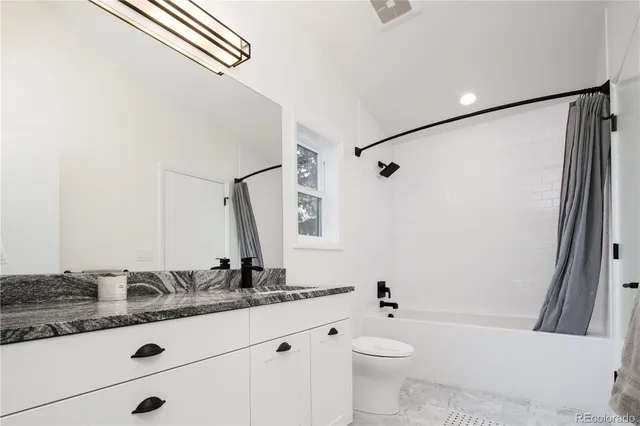 a bathroom with a granite countertop sink a toilet a mirror a vanity and shower