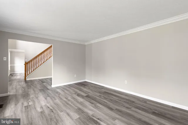 an empty room with wooden floor chandelier and windows