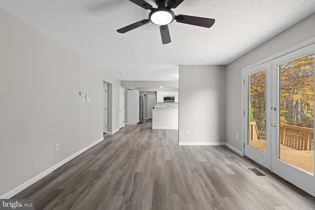a view of empty room with wooden floor and ceiling fan