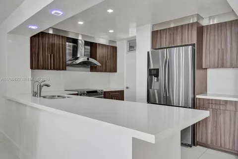 a kitchen with stainless steel appliances granite countertop a refrigerator a sink a stove and a refrigerator with wooden floor