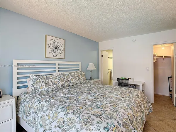 a large bed sitting in a bedroom and table chair