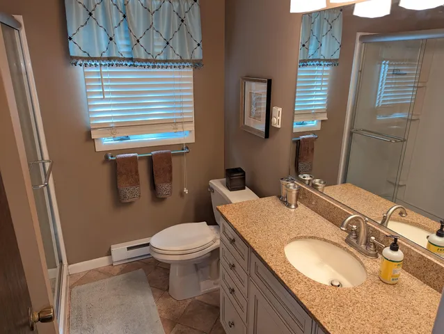 a bathroom with a granite countertop toilet sink and mirror