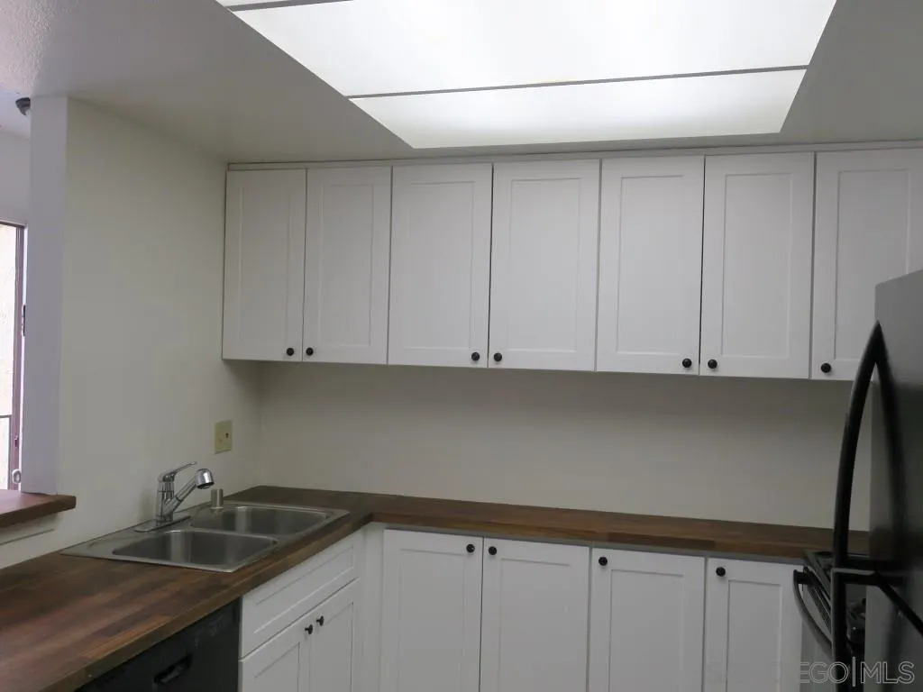 5938 Rancho Mission Road, Unit 134 San Diego, CA 92108 - Photo 3 of 36 a kitchen with granite countertop white cabinets and sink