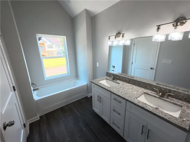 a bathroom with a granite countertop sink mirror and a bathtub