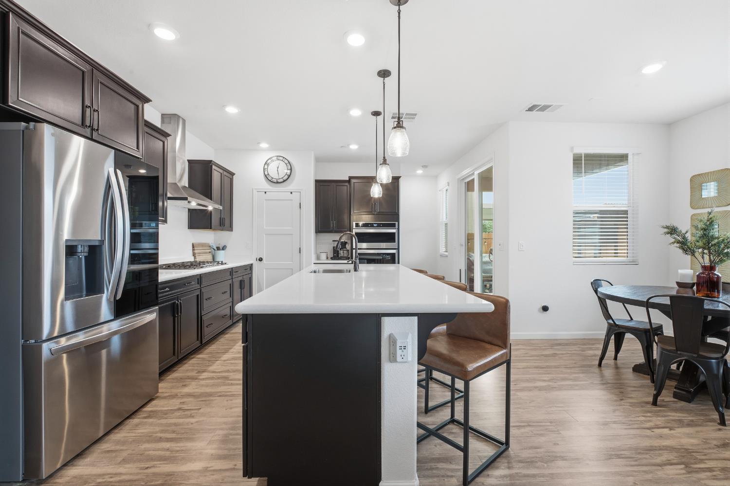 7240 Encore Way Roseville, CA 95747 - Photo 4 of 52 a kitchen with stainless steel appliances kitchen island granite countertop a refrigerator a stove a sink a dining table and chairs with wooden floor