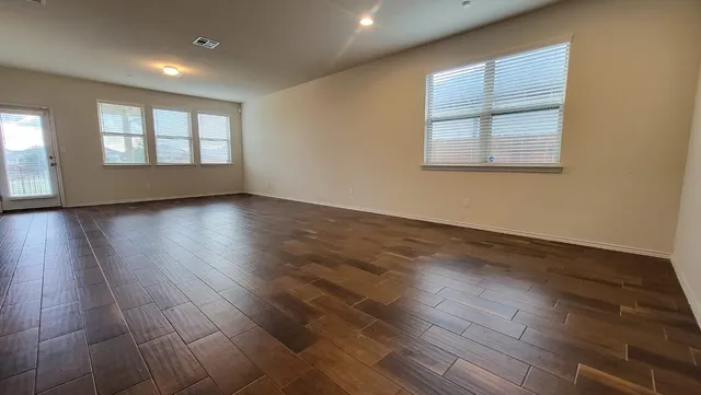 an empty room with wooden floor and windows