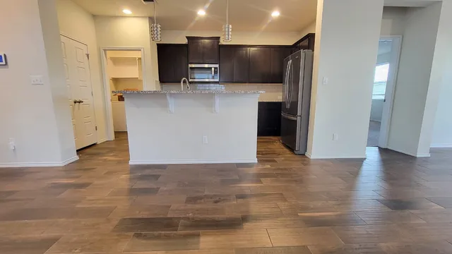a view of kitchen with stainless steel appliances granite countertop a refrigerator and a stove