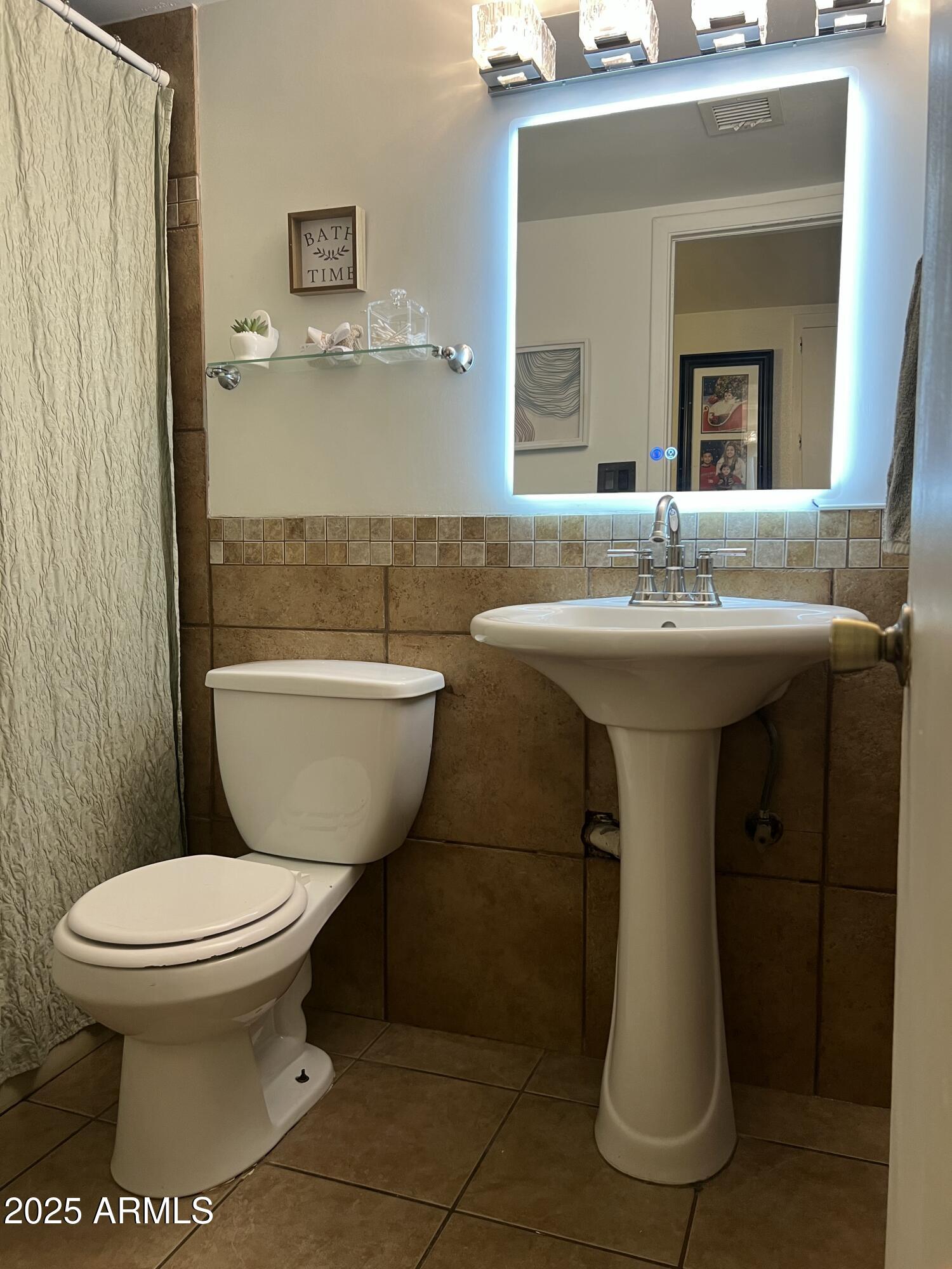 5212 North 42nd Lane Phoenix, AZ 85019 - Photo 12 of 16 a bathroom with a toilet sink and mirror