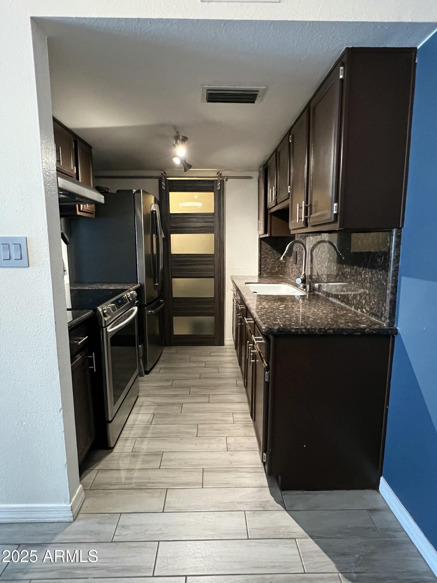 5212 North 42nd Lane Phoenix, AZ 85019 - Photo 8 of 16 a kitchen with stainless steel appliances granite countertop a sink stove and refrigerator