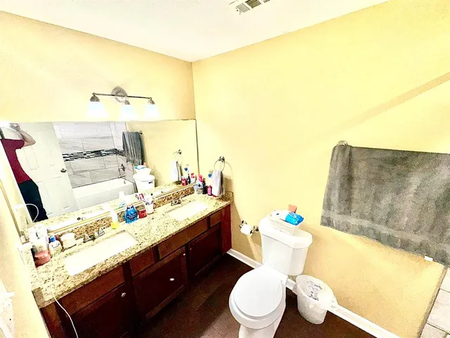 a bathroom with a granite countertop sink mirror vanity and toilet