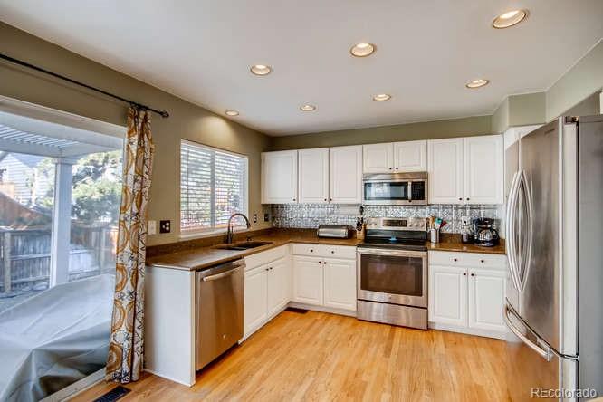 9629 Sydney Lane Highlands Ranch, CO 80130 - Photo 11 of 34 a kitchen with stainless steel appliances granite countertop a stove cabinets and a refrigerator