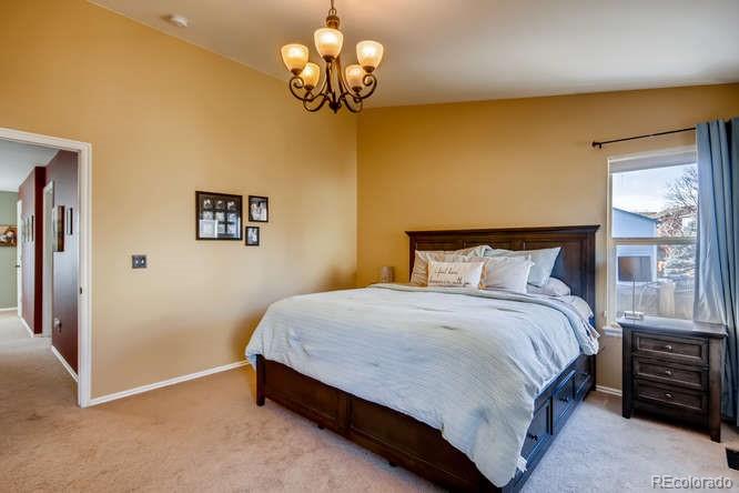 9629 Sydney Lane Highlands Ranch, CO 80130 - Photo 19 of 34 a bedroom with a bed and a chandelier