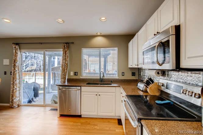 9629 Sydney Lane Highlands Ranch, CO 80130 - Photo 9 of 34 a kitchen with stainless steel appliances granite countertop a sink stove and cabinets