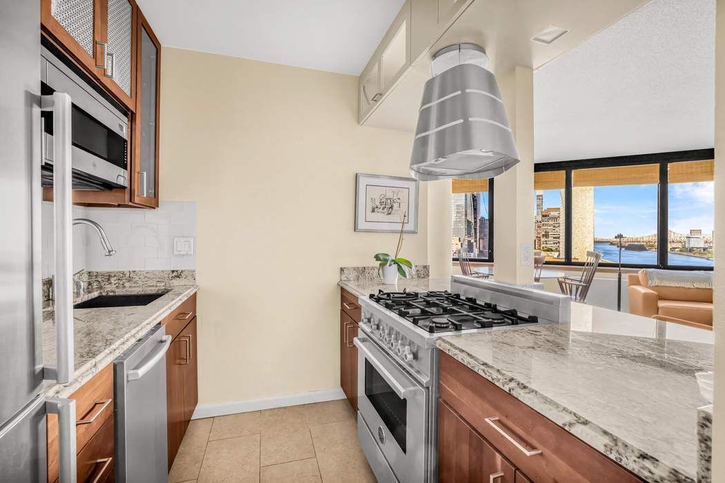415 East 37th Street, Unit 21J Manhattan, NY 10016 - Photo 3 of 14 a kitchen with stainless steel appliances granite countertop a stove and a sink