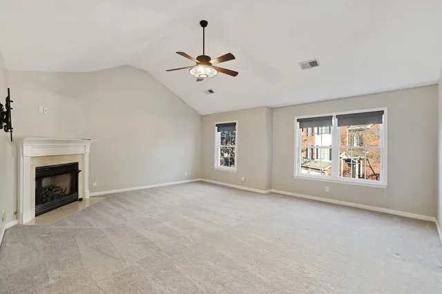 a view of an empty room with chandelier fan and fire place