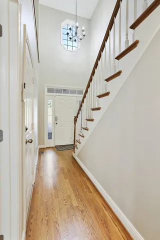 an empty room with wooden floor chandelier and windows