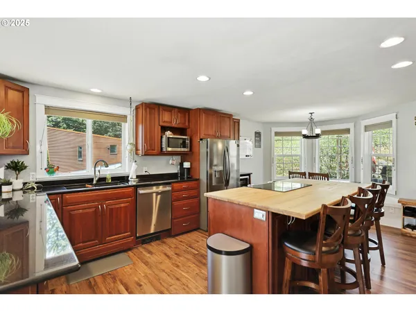 a kitchen with stainless steel appliances granite countertop a kitchen island hardwood floor sink stove dining table and chairs