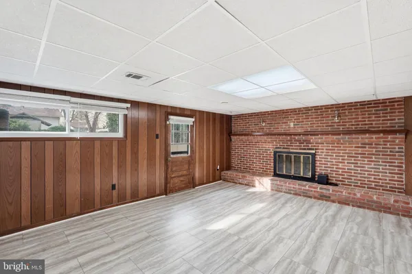 an empty room with wooden floor fireplace and windows
