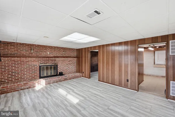 an empty room with wooden floor fireplace and windows