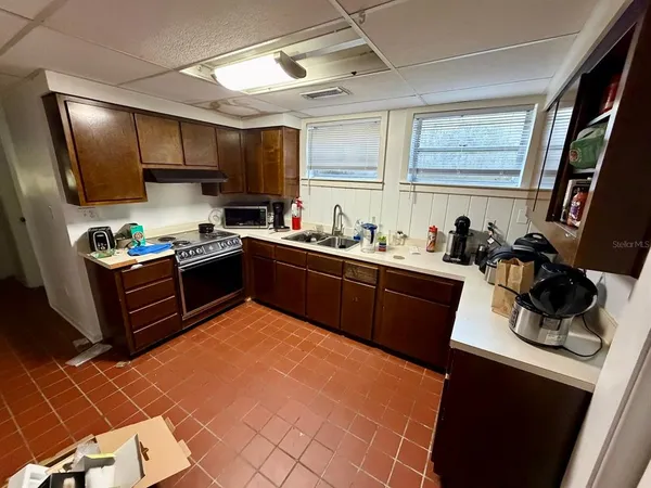 a kitchen with stainless steel appliances a sink a stove a refrigerator cabinets and a window