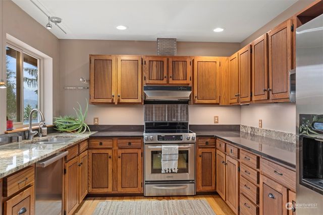 a kitchen with stainless steel appliances granite countertop a stove a sink and a microwave