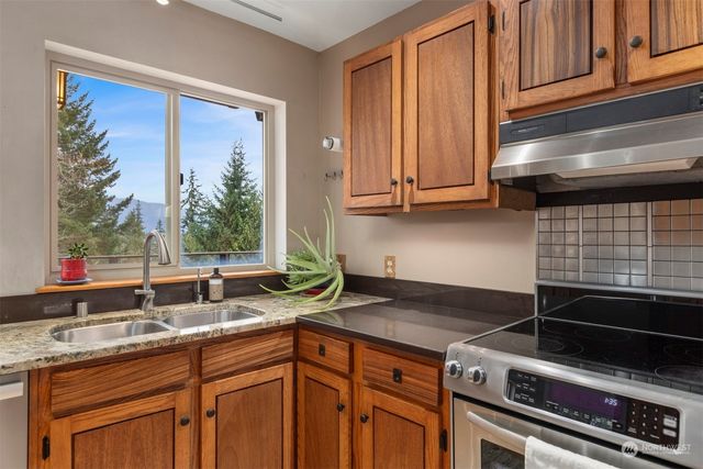 a kitchen with granite countertop a sink stainless steel appliances wooden floor and a counter top space