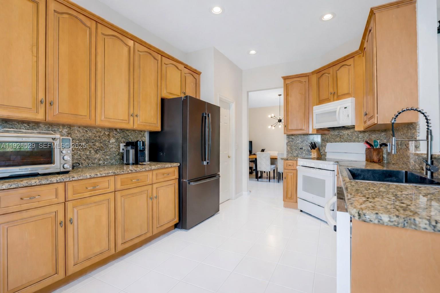 22065 Palm Grass Drive Boca Raton, FL 33428 - Photo 6 of 46 a kitchen with granite countertop a refrigerator stove top oven a sink and dishwasher