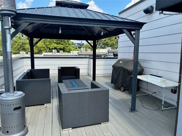 a view of a patio with table and chairs under an umbrella with a barbeque