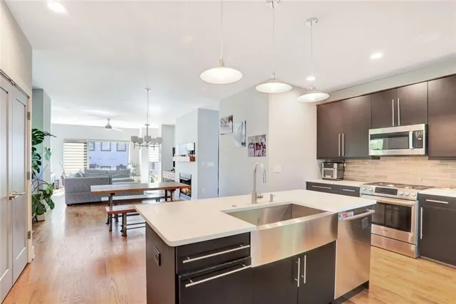 a kitchen with stainless steel appliances a stove a sink a oven a dining table and chairs