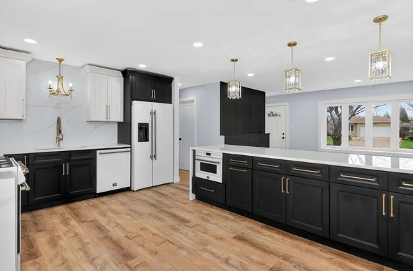 a large kitchen with stainless steel appliances kitchen island granite countertop a stove a sink dishwasher and a refrigerator with wooden floor